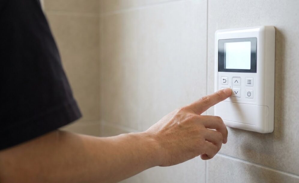 エコキュートのお湯の温度を調整するために、壁掛けリモコンを操作している様子