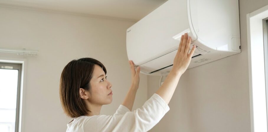 エアコンの前面パネルの端を「カチッ」と押し込んで閉める日本人女性