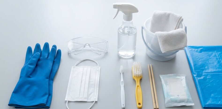エアコンのシロッコファン掃除に必要な道具一式。ゴーグル、マスク、青いゴム手袋、アルカリ電解水スプレー、バケツ、雑巾、歯ブラシ、ブラシ、割り箸、ウェットティッシュ、ビニール養生シートが並んでいる。