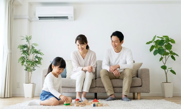 エアコンの内部クリーン機能により、カビの発生を抑え、清潔で健康的な空気が循環するリビングで快適に過ごす日本人家族。